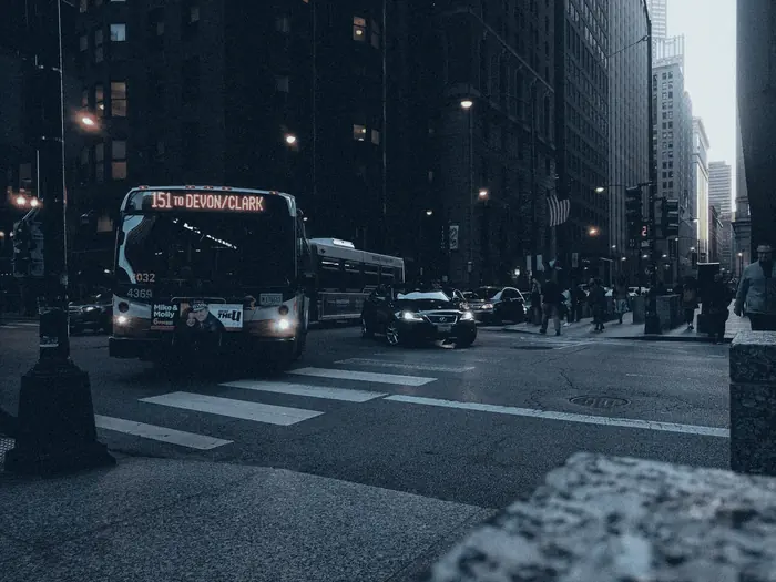 Colectivo urbano avanzando por una avenida al anochecer
